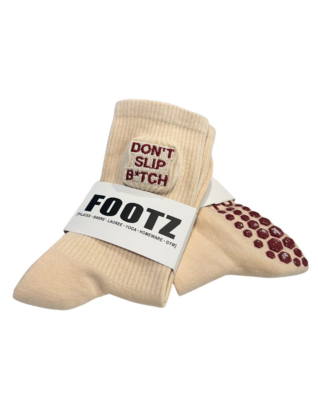 Tan "FOOTZ" Pilates socks feature "Don't Slip B*tch" embroidery and non-slip grip soles for yoga, barre, and gym workouts.
